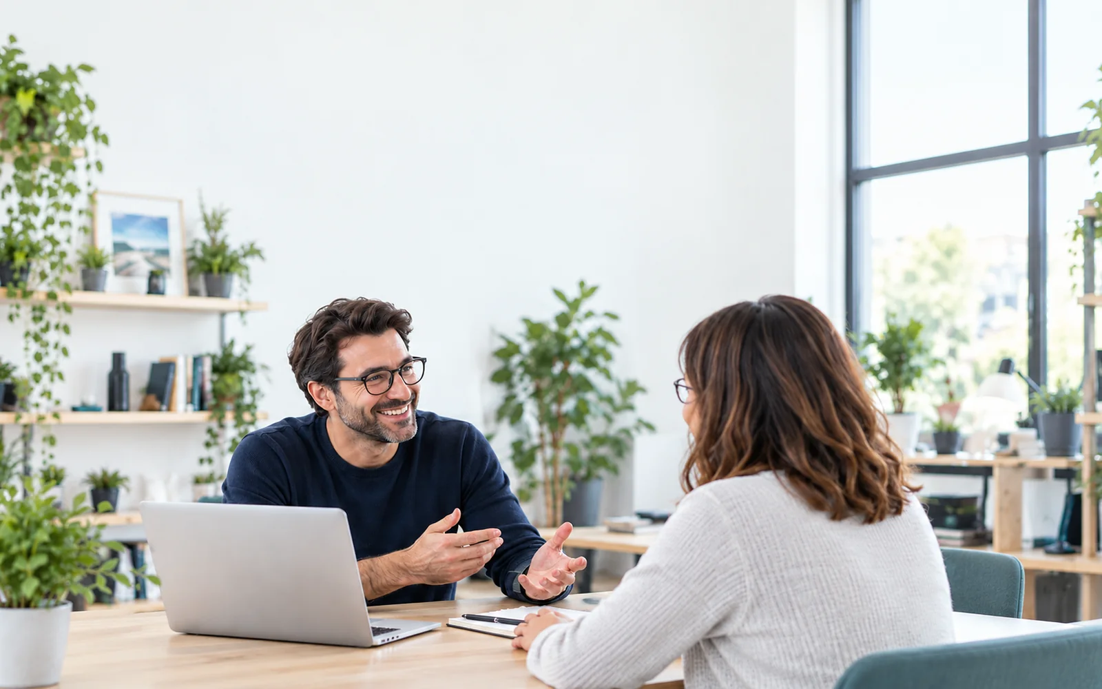 Un consultant indépendant avec lunettes échange avec sa cliente dans un bureau lumineux.